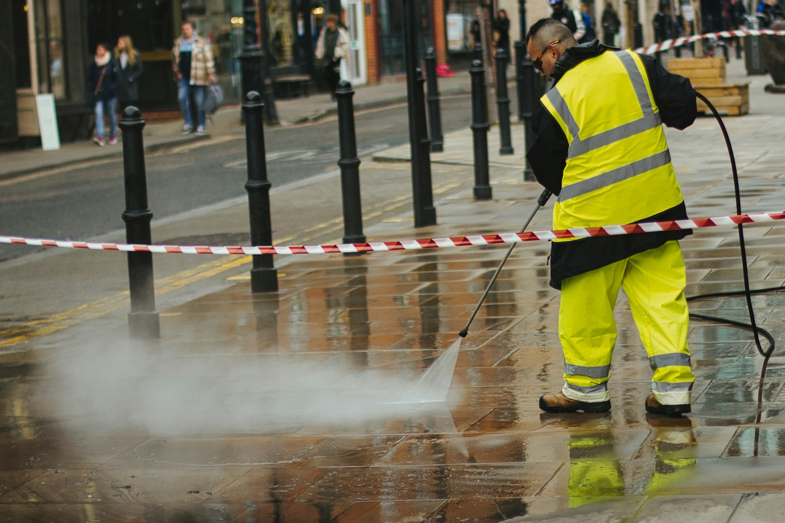 Worker pressure washing a paved outdoor area